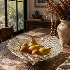 May include: A clear glass bowl with a wavy, textured rim and a footed base, containing five yellow and green pears. The bowl features a distinct ribbed pattern throughout its surface, creating a rippled effect that catches the light.