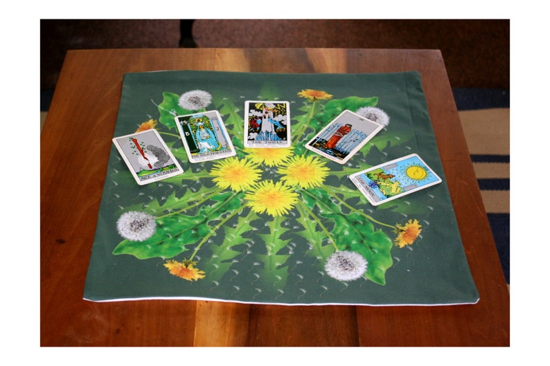 May include: A green tarot cloth with a dandelion design. Five tarot cards are laid out on the cloth. The cards are: The Chariot, The Tower, The Sun, The Magician, and Six of Swords.