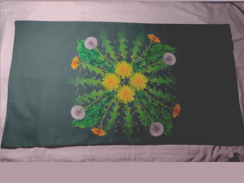 May include: A dark green pillowcase with a white and yellow dandelion flower design. The flowers are arranged in a circular pattern with green leaves.