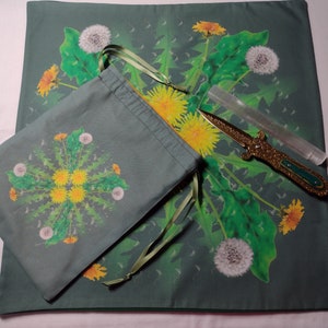 May include: A green cloth with a dandelion design, a green drawstring bag with a dandelion design, a clear quartz crystal wand, and a gold-colored dagger with a green handle.