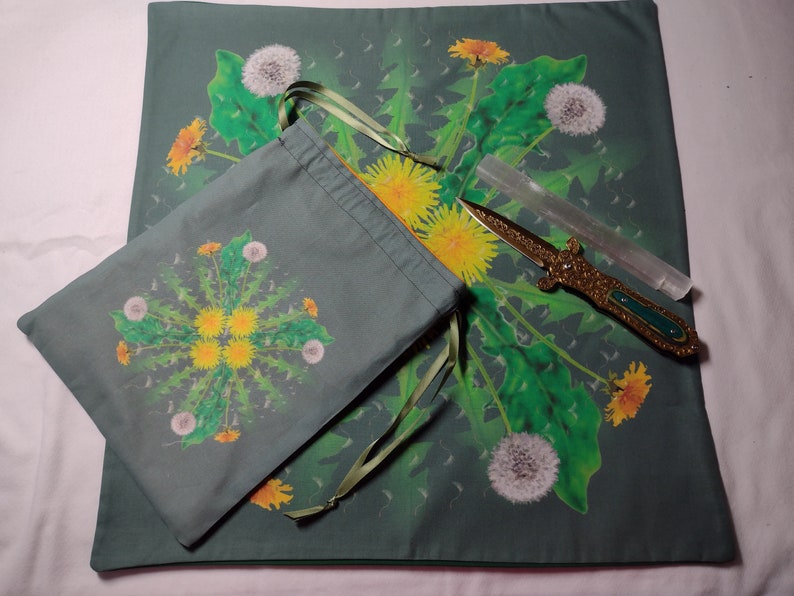 May include: A green cloth with a dandelion design, a green drawstring bag with a dandelion design, a clear quartz crystal wand, and a gold-colored dagger with a green handle.
