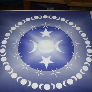 May include: A blue and white celestial-themed mat featuring a central design of a full moon, crescent moons, and stars. The design is surrounded by a ring of moon phases. The mat has a gradient blue background.