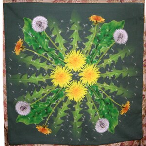 May include: A green fabric square with a symmetrical design of yellow dandelions and white dandelion seeds. The design is surrounded by green leaves.