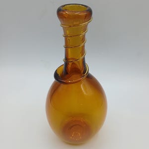 May include: A translucent amber glass vase with a bulbous base and a slender neck. The neck is wrapped in a continuous, spiraling coil of thin, clear glass that extends from the rim down to the top of the rounded body of the vessel.