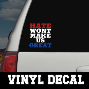 May include: A vinyl decal with the message "HATE WON'T MAKE US GREAT" in red, white, and blue lettering. The decal is displayed on a car window. The words "VINYL DECAL" are printed in white at the bottom.