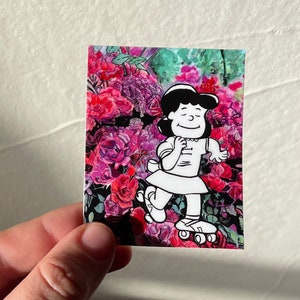 May include: A black and white illustration of a girl on roller skates in front of a pink and purple floral background.