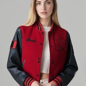 May include: A red and black varsity jacket with a large black letter "R" on the front. The jacket has black leather sleeves, a black and red striped collar and cuffs, and a small patch on the left sleeve. The jacket is buttoned up.