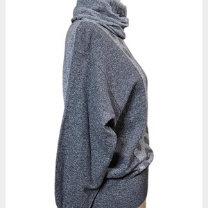 May include: A grey turtleneck jumper with long sleeves. The jumper has a textured knit and a high, folded collar. The sleeves are long and the overall style is casual. The jumper is displayed on a mannequin.