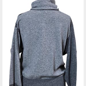 May include: A grey turtleneck jumper with long sleeves. The jumper has a ribbed hem and cuffs, and the sleeves are a darker shade of grey. The jumper is displayed on a mannequin.