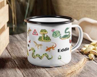 Peut inclure: Une tasse en émail blanc avec un bord et une poignée noirs. La tasse présente un motif de dessin animé de serpents, de lézards et d'autres reptiles. Le nom "Eddie" est imprimé sur la tasse.