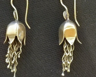 May include: A pair of silver earrings with a bell-shaped design and a dangling chain of small silver beads.