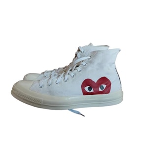 Può includere: Sneakers alte bianche con un motivo a forma di cuore rosso con due occhi. Le sneakers hanno lacci bianchi e una suola in gomma bianca. Queste classiche sneakers sono adatte per l'abbigliamento casual.