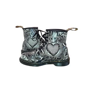 Könnte beinhalten: Schwarz-weiße Lederstiefel mit Herz- und Kronendesign. Die Stiefel haben einen Schnürverschluss und eine dicke Sohle.