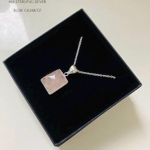 May include: A silver necklace with a square rose quartz pendant. The necklace is in a black box with the text "KARMENS KREATIONS 925 STERLING SILVER ROSE QUARTZ".