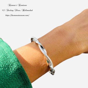 Può includere: Un bracciale rigido intrecciato in argento con finitura testurizzata. Il testo Karmen's Kreations, 925 Sterling Silver, Hallmarked e https://karmenstearoom.com/ è visibile nell'angolo in alto a sinistra dell'immagine.