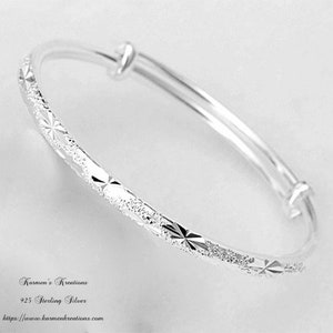 May include: A silver adjustable bracelet with a textured band featuring starburst and diamond-shaped patterns. The bracelet is made of 925 sterling silver. Text on the image reads "Karmen's Kreations" and "https://www.karmenkreations.com."
