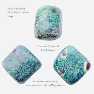 May include: Three polished Ruby in Fuchsite tumblestones. The stones are a mix of green and blue-grey with red ruby inclusions. The text on the image reads "Ruby in Fuchsite, Size: 30mm to 40mm, Large, Grade AAA Polished Tumblestones."