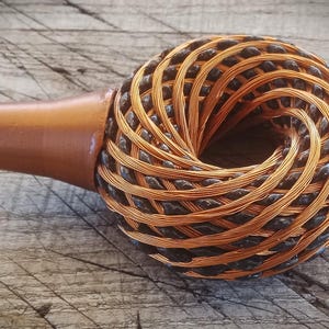 Può includere: Una bobina di filo di rame e nero a forma di toro, con un manico in plastica marrone.