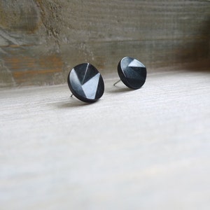 May include: A pair of black geometric stud earrings. The earrings are round and have a faceted design.