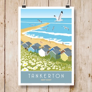 Op de afbeelding: Een kleurrijke illustratie van strandhuisjes op een grasbegroeide klif met uitzicht op een blauwe zee met witte golven. De lucht is blauw met witte wolken en er vliegen zeemeeuwen over. De tekst "Tankerton Kent Coast" staat onderaan de afbeelding.