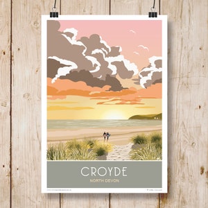 Può includere: Un'illustrazione colorata di una scena di spiaggia con una coppia che cammina su un sentiero verso l'oceano. Il cielo è di un rosa e un arancio vibrante con nuvole soffici. Il testo "CROYDE NORTH DEVON" è in basso nell'immagine.