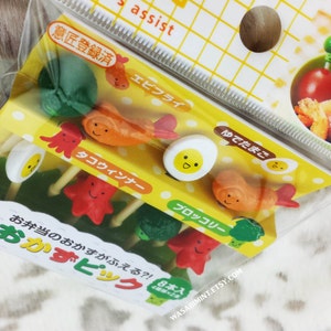 Puede incluir: Un conjunto de ocho pinchos para comida coloridos con diferentes dise&ntilde;os, incluyendo un pulpo, un camar&oacute;n, un huevo y br&oacute;coli. Los pinchos est&aacute;n hechos de pl&aacute;stico y est&aacute;n dise&ntilde;ados para ser utilizados en loncheras o para fiestas. El empaque es amarillo y presenta texto japon&eacute;s.