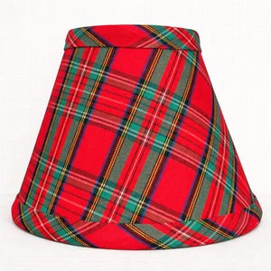 May include: A red plaid lampshade with green, yellow, and white accents. The lampshade has a classic tapered shape and is made of fabric. The plaid pattern is a traditional design, suitable for various home decor styles.