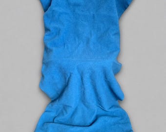 May include: A bright blue, soft, textured garment with a ruffled trim at the bottom. The fabric is gathered and draped, creating a flowing appearance. The trim is a lighter shade of blue, adding a delicate contrast to the main body of the item.