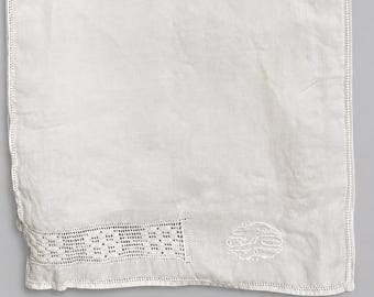May include: A white linen towel with a decorative embroidered border and a detailed openwork lace panel. The towel features an embroidered monogram in the lower right corner and a stitched edge.