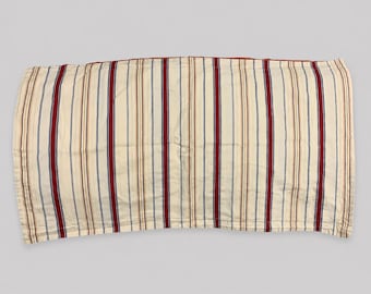 May include: A rectangular fabric textile featuring a repeating vertical striped pattern in shades of cream, deep red, and navy blue. The material has a visible quilted texture with stitched lines running parallel to the stripes across the surface.
