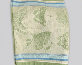 May include: A rectangular textile featuring a light green background with printed green butterfly illustrations and numbered labels. The fabric is bordered by horizontal stripes in shades of cream, light blue, and dark green along the top and bottom edges.