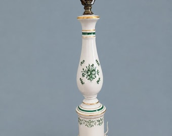 May include: A white ceramic lamp base with a tall, slender, baluster-shaped body. It features green floral patterns, horizontal green bands, and gold-painted trim. The base is square, and the top includes a brass-colored metal light socket.