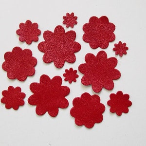 Peut inclure: Une collection d'ornements rouges en forme de fleurs de différentes tailles. Les ornements ont une surface texturée et sont dispersés sur un fond blanc. Ces éléments décoratifs pourraient être utilisés pour l'artisanat ou d'autres projets créatifs.