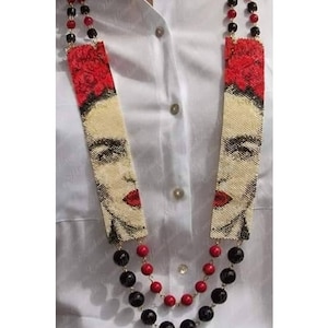 May include: A beaded necklace featuring a portrait of Frida Kahlo. The necklace is made of black and red beads and features a beaded portrait of Frida Kahlo with a red flower in her hair. The text "Realizzato da Conchita Montalbano Design Patrizia Bijoux" is at the bottom of the image.