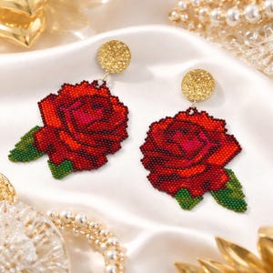 May include: A pair of beaded rose earrings. The earrings feature a red rose design with green leaves, attached to gold-colored circular studs. The roses are detailed with various shades of red and pink beads.