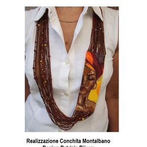 Può includere: Una collana di perline multifilo con un ritratto di perline di una donna con un foulard in testa. La collana è realizzata con perline marroni, rosse e gialle. Il ritratto è in tonalità di marrone, arancio e giallo. Il testo "Realizzazione Conchita Montalbano Design Patrizia Bijoux" è in fondo all'immagine.
