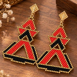 May include: A pair of geometric drop earrings crafted from small red and black beads arranged in a triangular pattern. Each earring features a gold-toned diamond-shaped stud at the top with a leaf-like etched design and a dangling beaded frame.