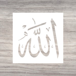 Peut inclure: Un pochoir blanc représentant la calligraphie arabe du mot "Allah". Le pochoir est carré et repose sur une surface en bois brun clair. La calligraphie est dans une écriture stylisée.