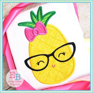 May include: Embroidered pineapple with a pink bow and black glasses. The pineapple is yellow with a green top and a textured surface. The design is on a white background.