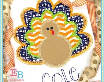 May include: Embroidered design of a brown turkey with orange, white and green feathers. The turkey is surrounded by a blue and orange patterned border. The name "COLE" is embroidered below the turkey.