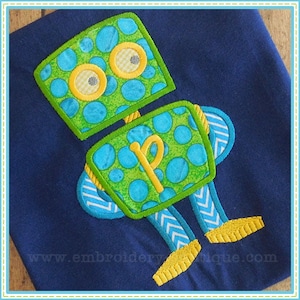 May include: A green and blue robot with yellow polka dots and a yellow letter "P" on its chest. The robot is embroidered on a dark blue fabric.