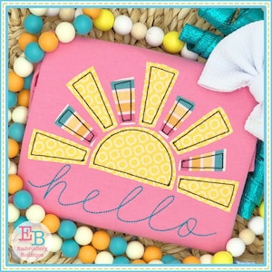 May include: Pink children's shirt with a yellow sun and the word "hello" embroidered on it. The sun has a pattern of small circles and the rays are striped with different colors.