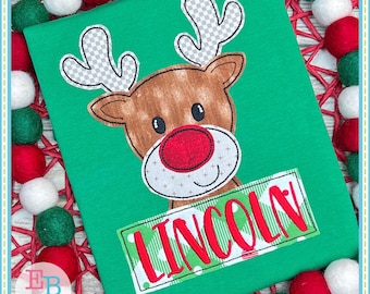 May include: Green t-shirt with a red and white reindeer applique and a green and white banner with the name "LINCOLN" in red.