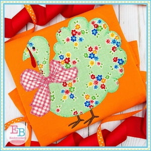 May include: A green and pink applique turkey with a gingham bow. The turkey is on an orange background.