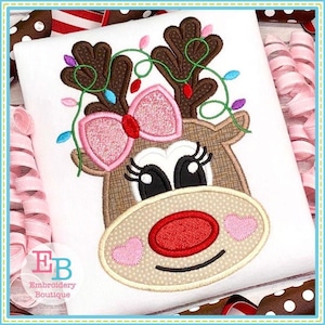 May include: Embroidered design of a brown reindeer with pink glitter bow, red nose, and pink hearts on its cheeks. The reindeer has green vines with colorful lights wrapped around its antlers.
