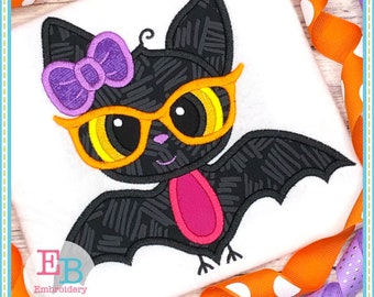 May include: A black bat with a purple bow and orange sunglasses. The bat has a pink tongue sticking out.