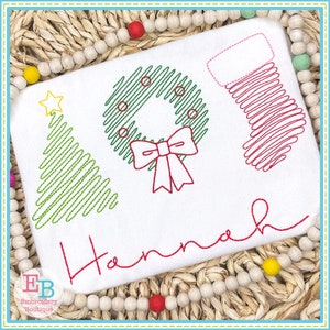 May include: White fabric featuring embroidered Christmas motifs: a tree, wreath, and stocking. The name "Hannah" is embroidered in red script. The design is outlined in green and red.