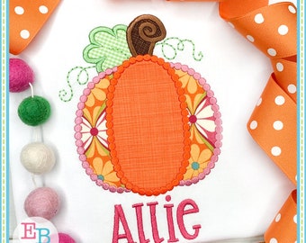 May include: A white t-shirt with an embroidered pumpkin design. The pumpkin is orange with a pink and orange floral pattern around the edge. The stem is brown with a green leaf. The name "Allie" is embroidered in pink below the pumpkin.