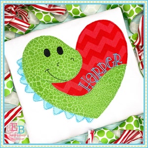 May include: Green dinosaur applique with a red heart and the name "Harper" embroidered in blue on a white t-shirt.