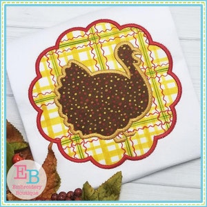May include: A brown and gold turkey applique with a yellow and green plaid background. The turkey is surrounded by a red scalloped border.